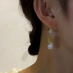 Side angle view of gold leaf teardrop pearl dangle earring worn on ear