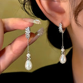 Silver baguette crystal teardrop pearl drop dangle earrings, worn on ear and held in hand