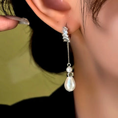 Close-up of silver baguette crystal teardrop pearl drop dangle earring worn on ear
