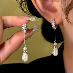 Silver baguette crystal teardrop pearl drop dangle earrings, worn on ear and held in hand