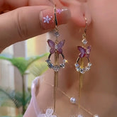 Purple butterfly crystal gold tassel drop earrings, pair held in hand