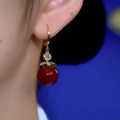 Model showcasing the dangle and style of the 14K Gold-Plated Zircon Red Pearl Earrings