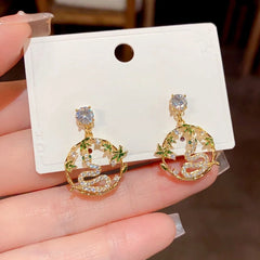 Pair of gold bamboo snake CZ dangle earrings on white jewelry card