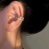 Sparkling gold crystal star ear cuff worn on a woman's ear, closeup