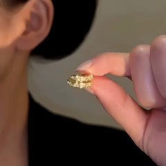 Fingers holding gold star ear cuff, jewelry detail closeup
