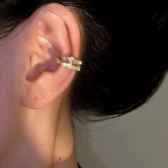 Sparkling gold crystal star ear cuff worn on a woman's ear, closeup