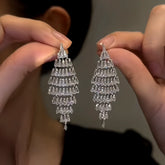 Pair of sparkling silver tiered crystal drop earrings held in hands