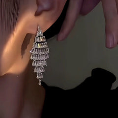 Close-up of sparkling silver tiered crystal drop earring on ear
