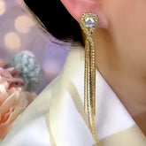 Gold rhinestone long tassel drop earring worn on ear close-up