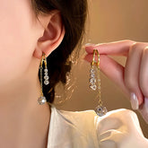 Gold double drop cubic zirconia hoop dangle earrings, one worn one held in hand