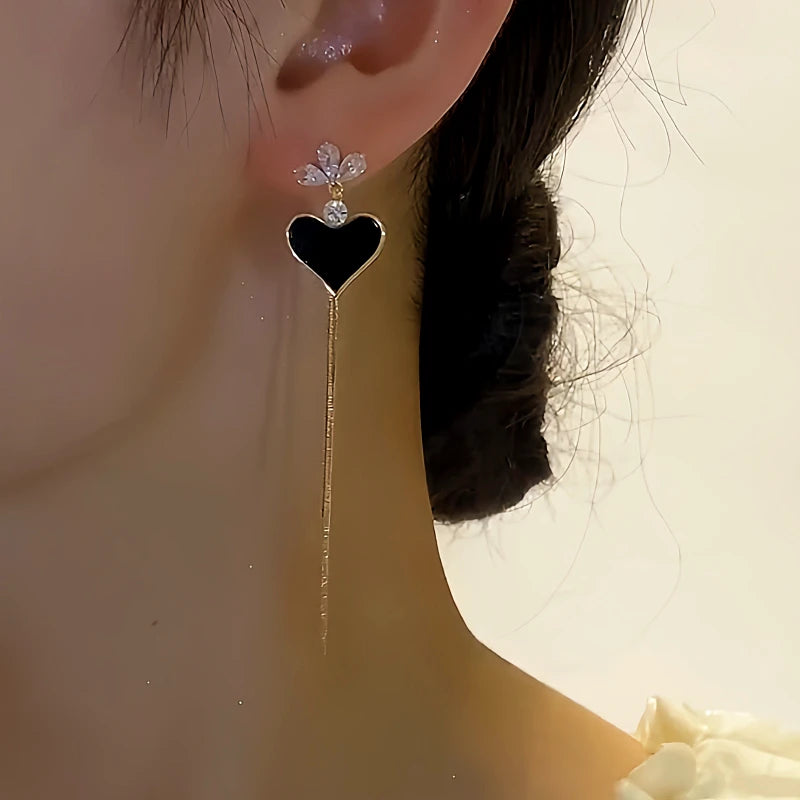 Angled view of the 14K Gold-plated Black Heart Tassel Earrings