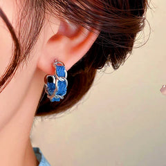 Model showcasing the dangle and style of the 14K Gold-plated Blue C-Shaped Earrings