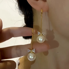 Model showcasing the dangle and style of the 14K Gold-plated Bow Long Pearl Ear Hook Earrings