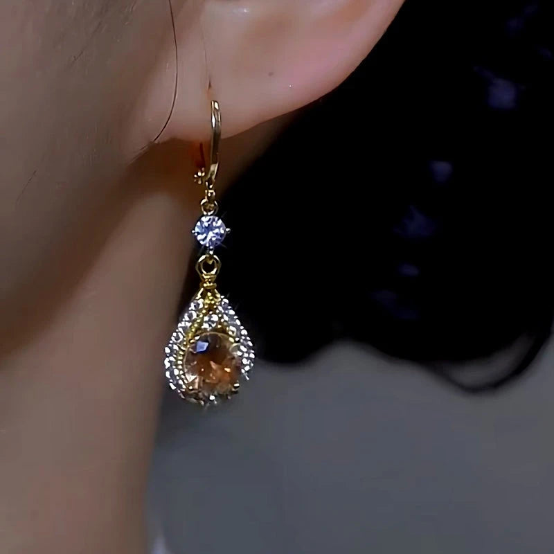 Model showcasing the dangle and style of the 14K Gold-plated Brown Diamond Crystal Earrings