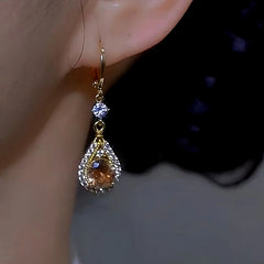 Model showcasing the dangle and style of the 14K Gold-plated Brown Diamond Crystal Earrings