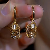 Pair of vintage gold champagne crystal drop huggie hoop earrings, closeup held in hand