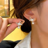 Dainty silver hollow butterfly pearl drop earrings, one worn on ear one held in hand