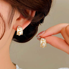 Vintage women's white enamel gold pearl stud earrings, one worn on ear, one held by hand