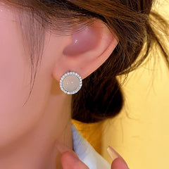 Closeup of silver round milky white halo CZ stud earring on ear