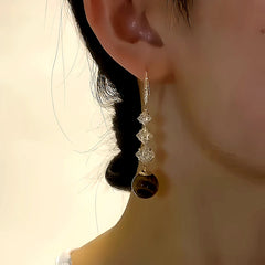 Model showcasing the dangle and style of the 14K Gold-plated Geometric Diamond Pearl Earrings