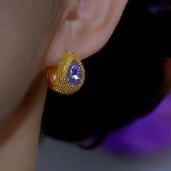 Textured gold teardrop purple gemstone stud earring on ear, front angle view