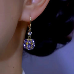 Side view of gold purple rhinestone ball dangle earring on ear