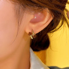 Side angle view of women's gold twisted mini hoop earring with brown cube crystals on ear