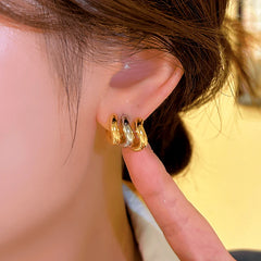 Model showcasing the dangle and style of the 14K Gold-plated Wavy Three-Layer Stud Earrings
