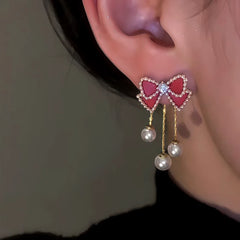 Model showcasing the dangle and style of the 14K Gold Plated Red Bow Pearl Tassel Earrings