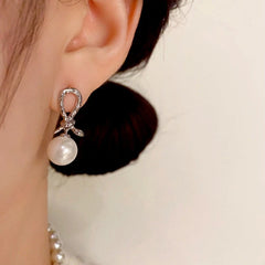 Model showcasing the dangle and style of the 14K Gold Plated Snake Knotted Pearl Earrings