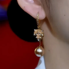 Model showcasing the dangle and style of the 14K Gold Plated Zircon Cat's Eye Stone Maple Leaf Brown Pearl Earrings