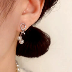 Model showcasing the dangle and style of the 14K Gold Plated Zircon Knot Pearl Tassel Earrings