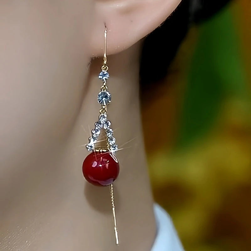 Model showcasing the dangle and style of the 14K Gold Plated Zircon Red Pearl Threader Earrings