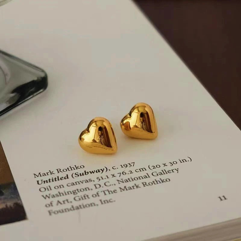Model showcasing the dangle and style of the 18K Gold-Plated Heart Stud Earrings