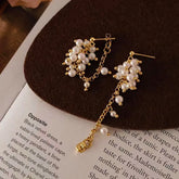 Women's gold pearl cluster dangle earrings displayed on a book page with brown felt