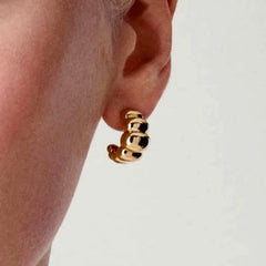 Gold chunky beaded C-hoop earring worn on ear, close-up side view