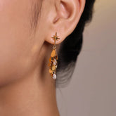 Gold starburst teardrop crystal dangle earring worn on ear