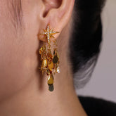 Gold starburst dangling disc drop earring with crystal accents, worn on ear