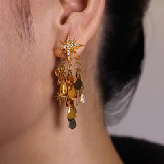 Gold starburst dangling disc drop earring with crystal accents, worn on ear