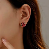 Woman wearing red rose enamel gold trim stud earring on ear closeup