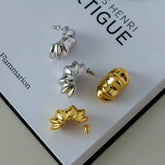Gold and silver sculptural ribbed statement hoop earrings on book page
