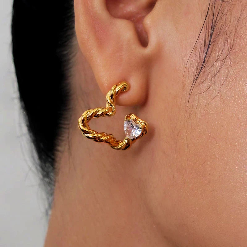 Close-up of gold twisted open heart stud earring with heart cubic zirconia on ear