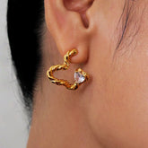 Close-up of gold twisted open heart stud earring with heart cubic zirconia on ear