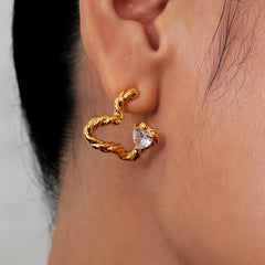 Close-up of gold twisted open heart stud earring with heart cubic zirconia on ear