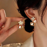Gold rhinestone star pearl dangle earrings, one worn on ear one held by hand
