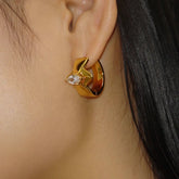 Gold marquise CZ huggie hoop earring worn on woman's earlobe