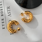 Gold quilted thick C-shaped hoop earrings on printed paper background
