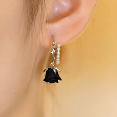Model showcasing the dangle and style of the Halloween 14K Gold-Plated Black Flower And Heart Earrings