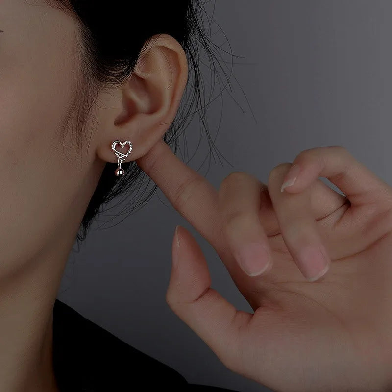 Model showcasing the dangle and style of the Sterling Silver Diamond Hollow Heart Bean Earrings