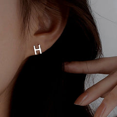 Model showcasing the dangle and style of the Sterling Silver Double-Sided Letter H Stud Earrings